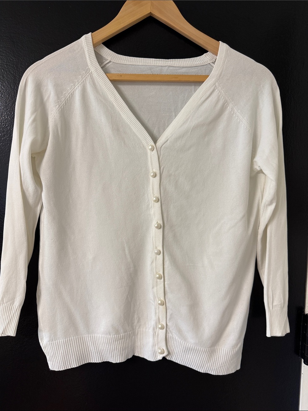 V-neck cardigan featuring a ribbed knit texture and pearl-style buttons.